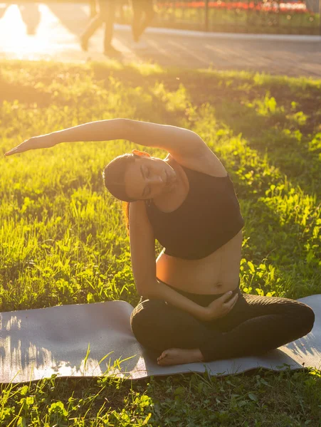 Gravid kvinna som motionerar på gräset på sommardagen. En hälsosam livsstil. — Stockfoto