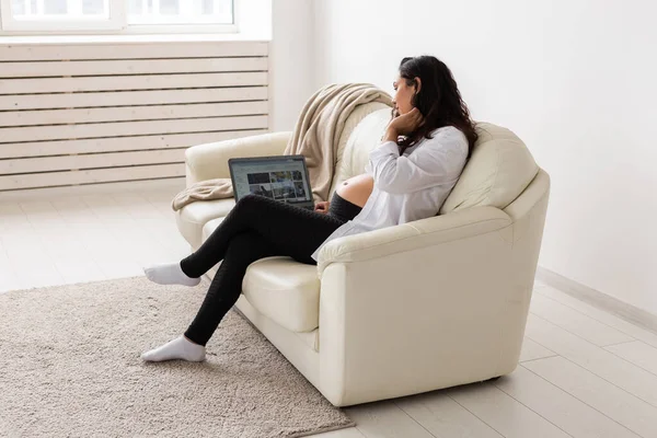 Latynoska kobieta w ciąży używająca laptopa siedzącego na kanapie w domu. Ciąża i informacje dotyczące koncepcji rodzicielstwa. — Zdjęcie stockowe