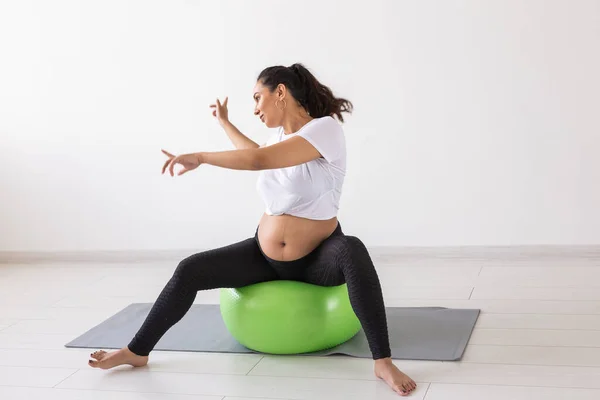 Mujer embarazada alegre baila mientras está sentado en la pelota de fitness. Embarazo de bienestar, estilo de vida saludable y concepto positivo. —  Fotos de Stock