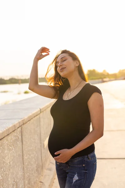 Gravid latinamerikansk kvinna på vall, rörande mage — Stockfoto