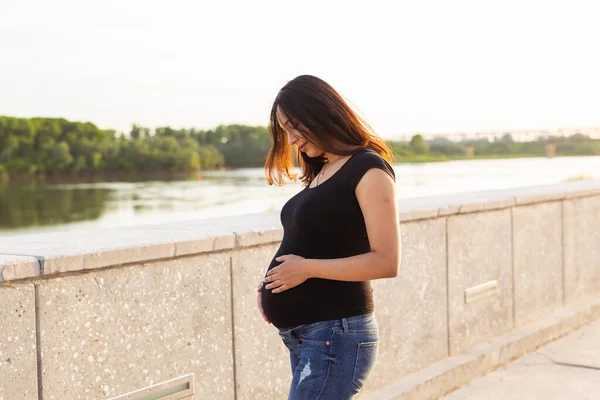 Retrato da mulher grávida hispânica a caminhar num parque ao pôr-do-sol. Conceito de gravidez e maternidade. — Fotografia de Stock