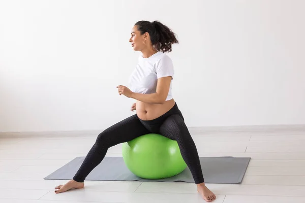 Mujer embarazada alegre baila mientras está sentado en la pelota de fitness. Embarazo de bienestar, estilo de vida saludable y concepto positivo. —  Fotos de Stock