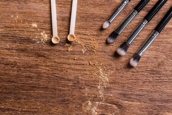 Mineral powder foundation with brushes on a wooden background with copy space. Eco-friendly and organic beauty products