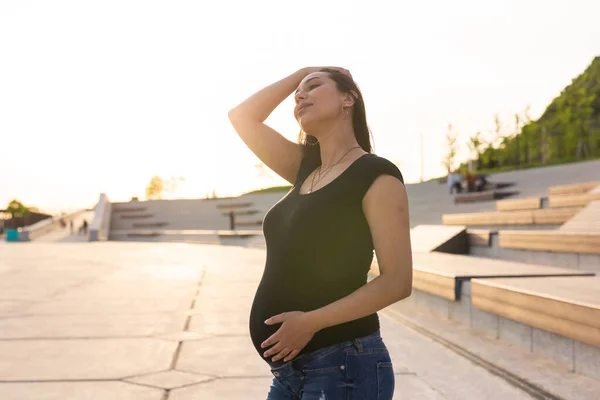 Gravid latinamerikansk kvinna i parken, vidrör magen — Stockfoto