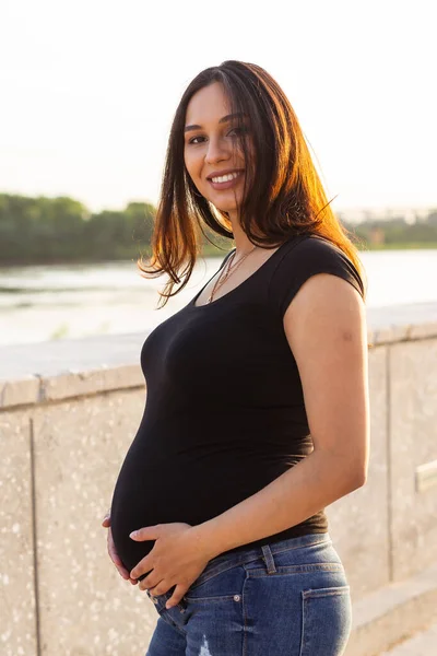 Porträtt av latinamerikansk gravid kvinna som går i en park vid solnedgången. Graviditet och moderskap koncept. — Stockfoto