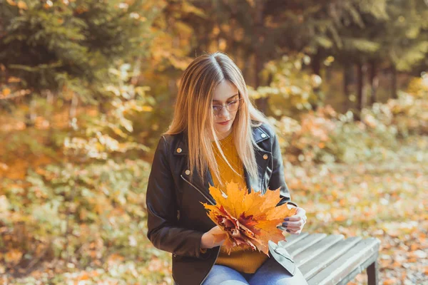 Mujer joven sosteniendo hojas de otoño en el parque de otoño. Concepto estacional, estilo de vida y ocio. — Foto de Stock