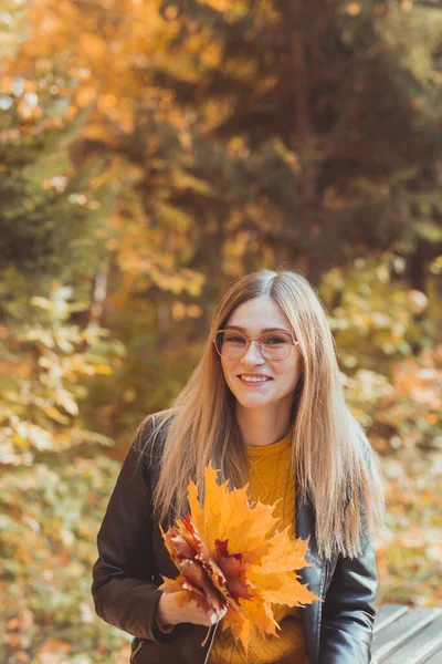 Cute smiley kobieta trzyma jesienne liście w jesiennym parku. Koncepcja sezonowości, stylu życia i wypoczynku. — Zdjęcie stockowe