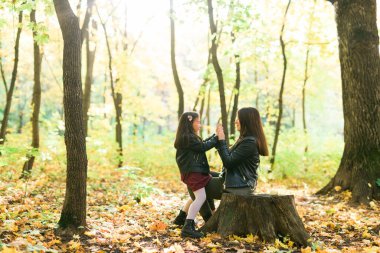 Anne ve kızı sonbahar sarı parkında birlikte vakit geçiriyorlar. Sezon ve tek ebeveyn kavramı.