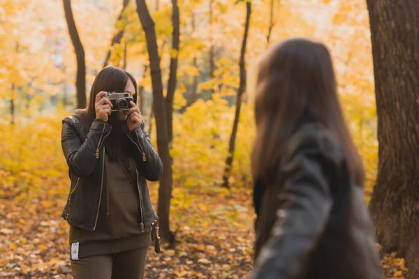 Madre tomando fotos de su hija carismática en cámara retro en el parque de otoño. Hobbies y concepto de ocio. — Foto de Stock
