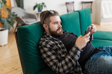Akıllı telefon kullanarak sosyal ağ sitesinde sörf yapan genç bir adam. Teknolojiler ve internet kavramı.