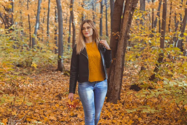 Dziewczyna trzyma spadające liście i spacery w jesiennym parku. Koncepcja sezonowa. — Zdjęcie stockowe