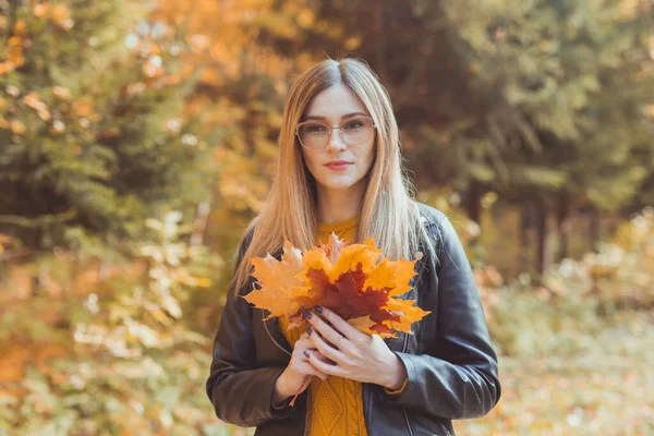 Roztomilá smajlík žena drží podzimní listí v podzimním parku. Sezónní, životní styl a koncepce volného času. — Stock fotografie