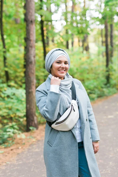Sonbahar parkının arka planında duran tesettürlü genç bir kadın. Modern Arap Müslüman kız. — Stok fotoğraf