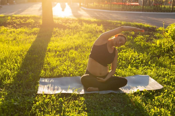 妊娠中の女性は夏の日に草の上でフィットネス演習を行う。健康的なライフスタイル. — ストック写真