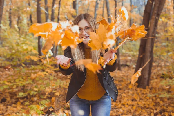 Feliz riéndose jovencita lanzando hojas en el parque de otoño. Temporada de otoño —  Fotos de Stock