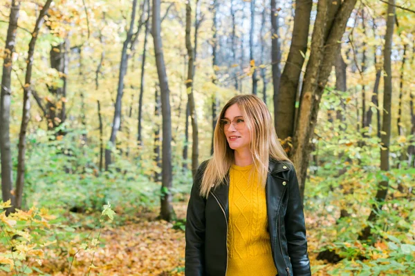 Jolie femme souriante tenant des feuilles d'automne dans le parc d'automne. Saisonnière, lifestyle and leisure concept. — Photo