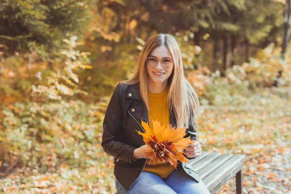 Mädchen hält abgefallenes Laub im Herbstpark. Saisonkonzept. — Stockfoto