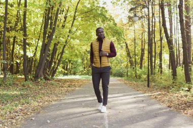 Afrikalı Amerikalı öğrenci sonbahar sezonunda parkta yürüyor.