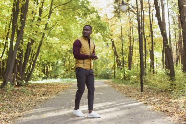 Afrikalı Amerikalı öğrenci sonbahar sezonunda parkta yürüyor.