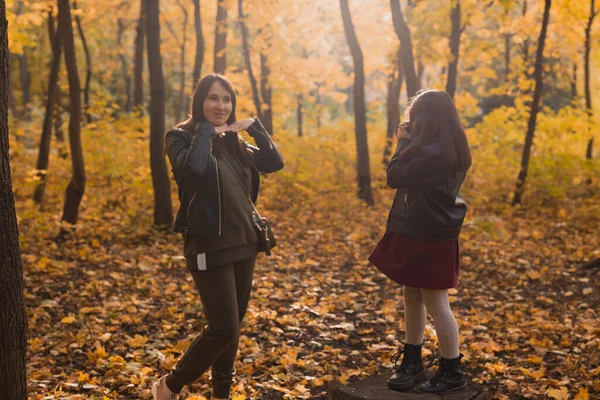 Bambino scattare foto sua madre sulla macchina fotografica retrò nel parco autunnale. Interessi e concetto di svago. — Foto Stock