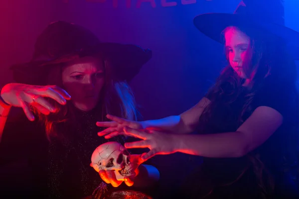 Две ведьмы на Хэллоуин делают зелье и колдуют в ночь Хэллоуина. Магия, праздники и мистическая концепция. — стоковое фото