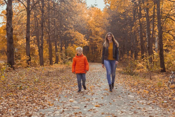 Mor och son går i höstparken och njuter av den vackra höstnaturen. Säsong, ensamstående förälder och barn koncept. — Stockfoto