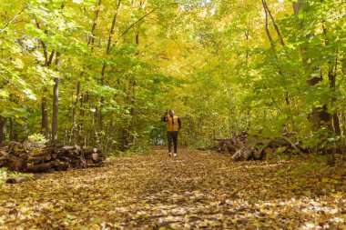 Afrikalı Amerikalı öğrenci sonbahar sezonunda parkta yürüyor.