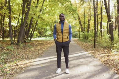 Afrikalı Amerikalı öğrenci sonbahar sezonunda parkta yürüyor.