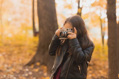 Sonbahar doğasında eski moda kamera kullanan bir kız çocuğu. Fotoğrafçı, sonbahar sezonu ve eğlence konsepti.