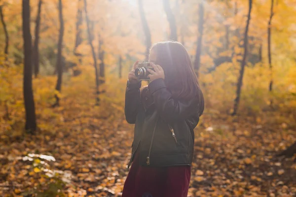 Маленькая девочка фотографируется со старой ретро-камерой осенью на природе. Концепция отдыха и хобби. — стоковое фото