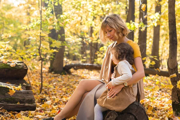 Jovem mãe com sua filhinha em um parque de outono. Temporada de outono, parentalidade e conceito de crianças. — Fotografia de Stock