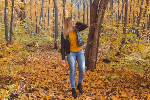 Mädchen hält umgefallenes Laub in der Hand und geht im Herbstpark spazieren. Saisonkonzept. — Stockfoto