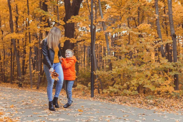 Mor och son går i höstparken och njuter av den vackra höstnaturen. Säsong, ensamstående förälder och barn koncept. — Stockfoto