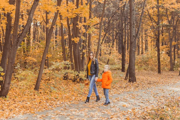 Mor och son går i höstparken och njuter av den vackra höstnaturen. Säsong, ensamstående förälder och barn koncept. — Stockfoto