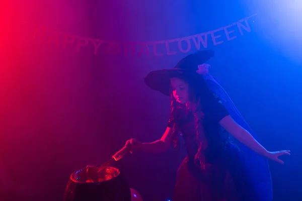 Hexenkind bereitet an den Halloween-Feiertagen einen Zaubertrank im Hexenkessel zu. — Stockfoto