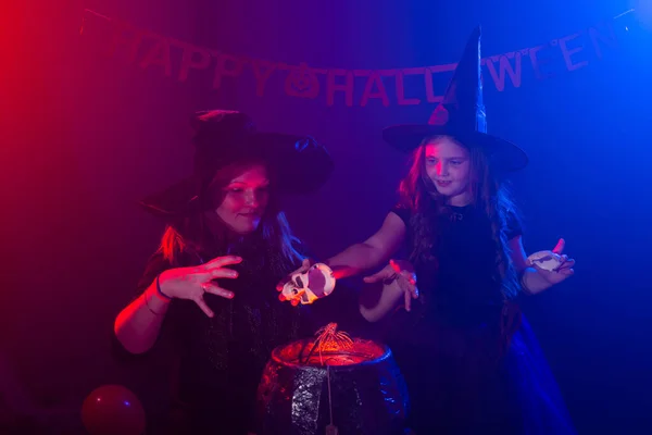 Två halloween häxor gör en trolldryck och trolla i halloween kväll. Magi, semester och mystiskt koncept. — Stockfoto