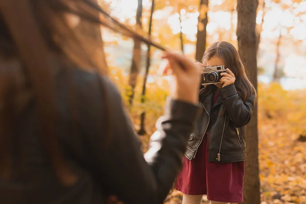 Niño tomando fotos de su madre en cámara retro en el parque de otoño. Hobbies y concepto de ocio. — Foto de Stock