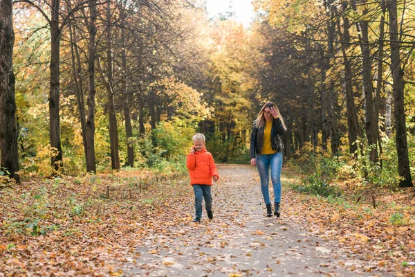 Moeder en zoon wandelen in het herfstpark en genieten van de prachtige herfstnatuur. Seizoen, eenouder- en kinderconcept. — Stockfoto