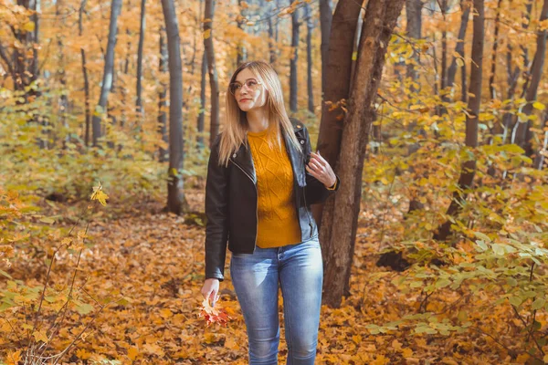 Cute smiley kobieta trzyma jesienne liście w jesiennym parku. Koncepcja sezonowości, stylu życia i wypoczynku. — Zdjęcie stockowe