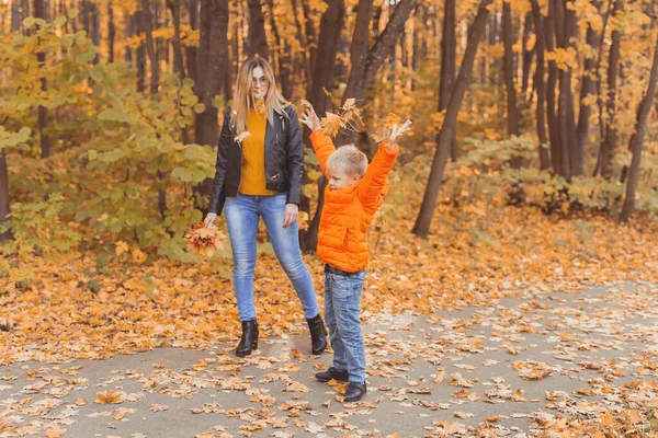 Moeder en zoon wandelen in het herfstpark en genieten van de prachtige herfstnatuur. Seizoen, eenouder- en kinderconcept. — Stockfoto