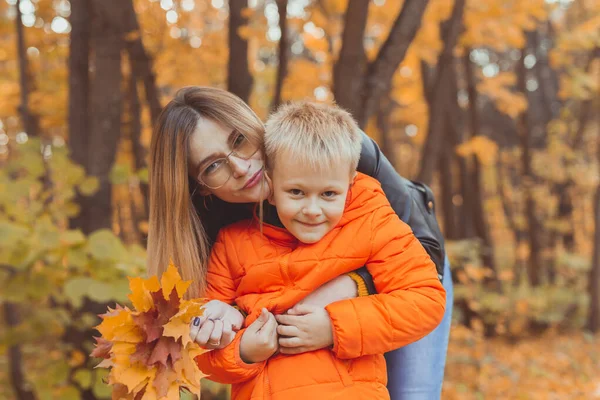 Mor kramar sitt barn under vandringen i höstparken. Höstsäsong och enförälderskoncept. — Stockfoto