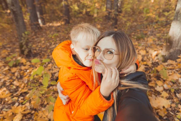 Hijo y madre se están tomando selfie y divirtiéndose en el parque de otoño. Concepto de temporada monoparental, de ocio y otoño. —  Fotos de Stock