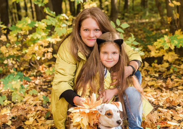 Mutter und kleine Tochter gehen bei Herbstwetter mit ihrem Jack Russell Terrier-Hund spazieren. Stilvolle kleine Tochter und ihre Mutter. Glückliche Kindheit. Draußen Porträt einer glücklichen Familie. — Stockfoto