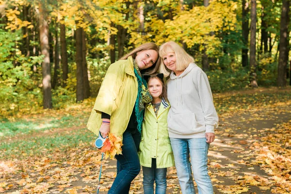 Porträt von drei Generationen glücklicher schöner Frau, die in die Kamera blickt, sich umarmt und in der herbstlichen Natur lächelt. — Stockfoto