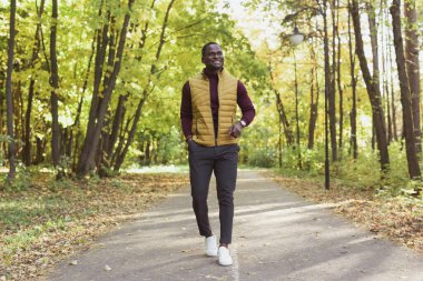 Erkek öğrenci sonbahar mevsiminde parkta yürüyor