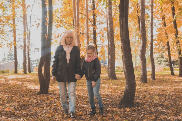 Büyükanne ve torunu sonbahar parkında. Nesil ve aile kavramı. — Stok fotoğraf