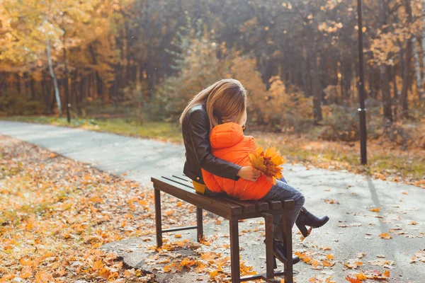 Samotna matka i chłopiec jesienią w parku siedzieć na ławce. Jesienny sezon i koncepcja rodziny. — Zdjęcie stockowe