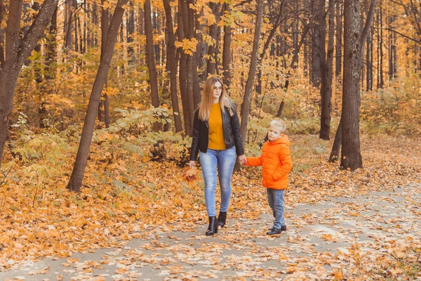 Mother and son walking in the fall park and enjoying the beautiful autumn nature. Season, single parent and children concept. — Stock Photo, Image