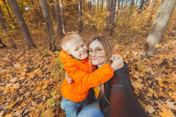 Hijo y madre se están tomando selfie y divirtiéndose en el parque de otoño. Concepto de temporada monoparental, de ocio y otoño. —  Fotos de Stock