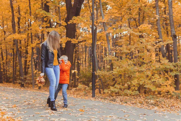 Anne ve oğlu sonbahar parkında yürüyor ve güzel sonbahar doğasının tadını çıkarıyorlar. Sezon, yalnız ebeveynler ve çocuklar konsepti. — Stok fotoğraf